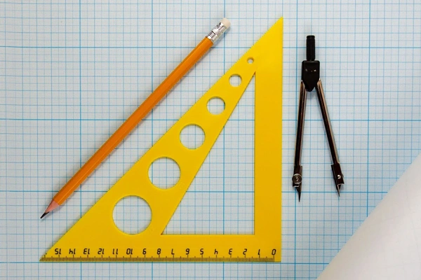 pencil, triangle, compass, laid out on graph paper