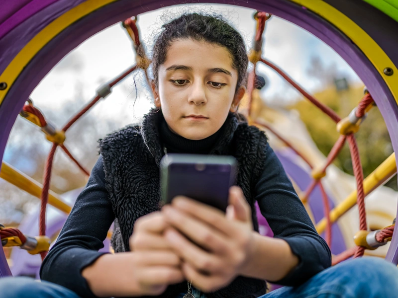 Little girl playing on mobile phone instead of enjoying the Park