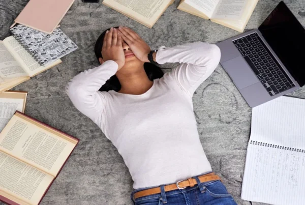 stressed out girl lying on the floor next to her school books and laptop